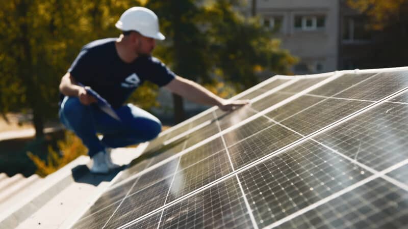 Gros plan d'un technicien inspectant la qualité et la stabilité des panneaux solaires. Parfait pour présenter l'entretien des énergies renouvelables et la précision de l'ingénierie.